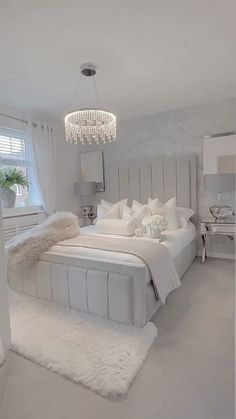 a white bedroom with a chandelier hanging from the ceiling and carpeted floor