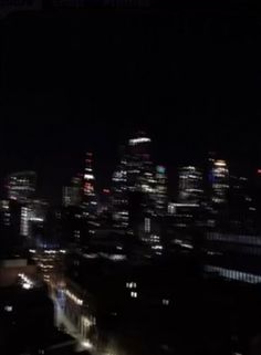 the city skyline is lit up at night with bright lights in the dark, including skyscrapers