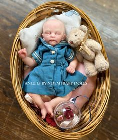 a baby doll in a basket with two teddy bears