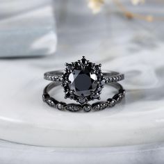 a black diamond engagement ring set on top of a white marble table with flowers in the background