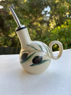 a white vase with a pipe sticking out of it's side sitting on a table