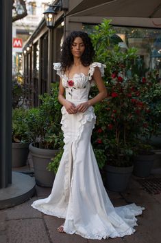 a woman in a white dress is standing outside