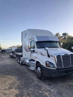 a semi truck is parked on the side of the road with other trucks behind it