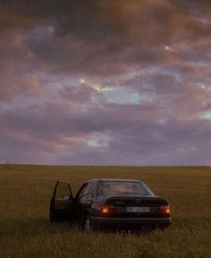 a car is parked in the middle of a field under a purple and blue sky