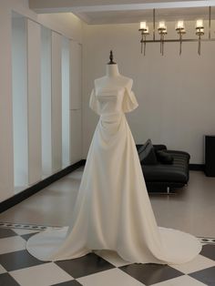 a white wedding dress on display in a room with black and white checkered flooring