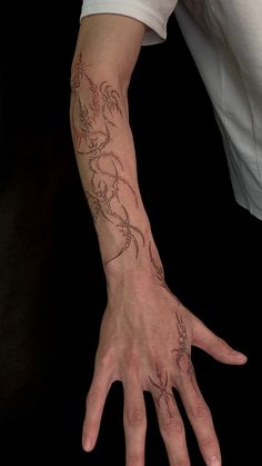 a person with a tattoo on their arm and hand is reaching out to touch the ground