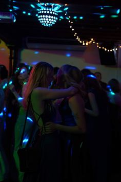 two women hugging each other in front of a group of people at a dance party