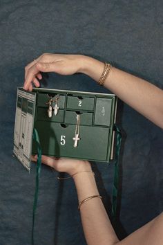 a woman is holding a green box with jewelry in it and her hands are on the side