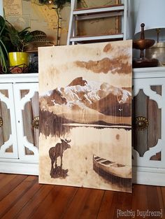 a painting sitting on top of a wooden floor next to a white cabinet and shelf