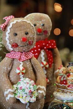 gingerbread man and woman ornaments on display in front of christmas tree with lights behind them