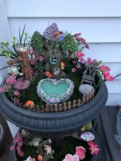 a potted planter filled with lots of flowers and plants next to a house