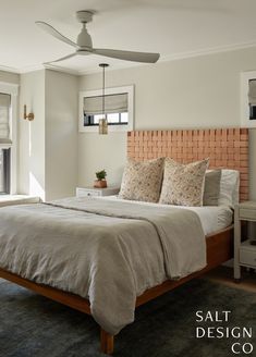 a bed sitting in a bedroom next to a window with a fan on top of it