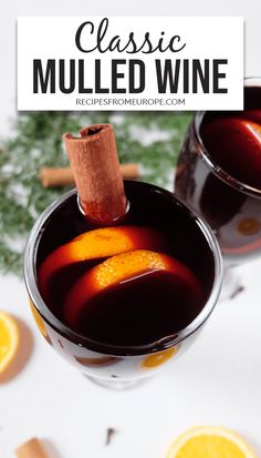 two glasses filled with mulled wine sitting on top of a white table next to orange slices