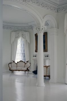 an elegant living room with white walls and columns