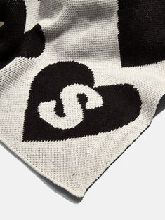 a black and white blanket with the letter c on it's side, laying down