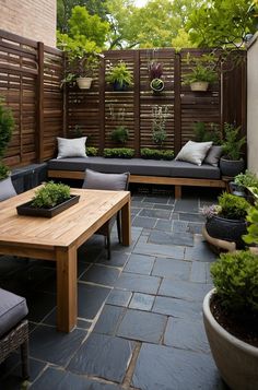 a wooden table sitting on top of a stone floor next to a bench and potted plants