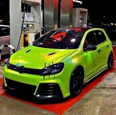 a green car is parked at a gas station