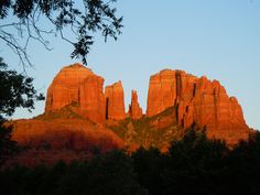 the sun is setting on red rock formations