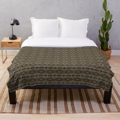 a bed sitting on top of a wooden floor next to a potted green plant