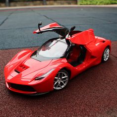 a red toy sports car sitting on top of a parking lot