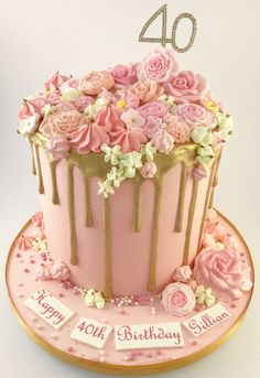 a birthday cake with pink flowers and gold drips on it's top is sitting on a plate