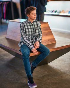 a young man sitting on top of a wooden bench