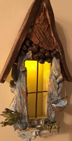 a birdhouse made out of wood and stone with a yellow light in the window