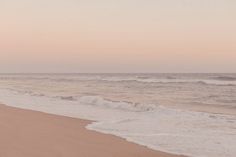 two people walking on the beach with surfboards