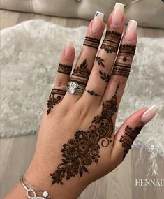 a woman's hand with henna tattoos on it and two rings in the middle