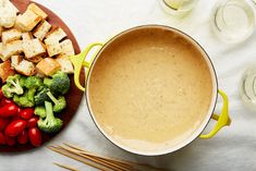 a pan filled with broccoli, tomatoes and tofu on top of a table