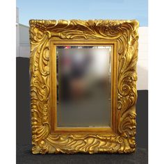 a gold framed mirror sitting on top of a floor