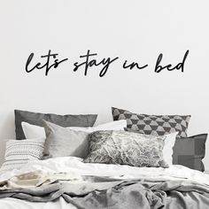 a bed sitting under a wall with the words let's stay in bed on it