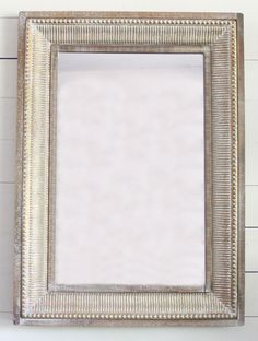 a silver framed mirror hanging on the wall