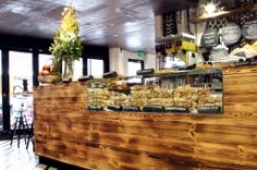 a wooden counter sitting inside of a restaurant with lots of food on top of it