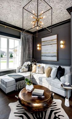 a living room filled with furniture and a chandelier hanging from the ceiling in front of a window