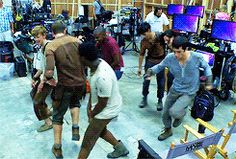 a group of young men standing around each other in front of televisions and monitors