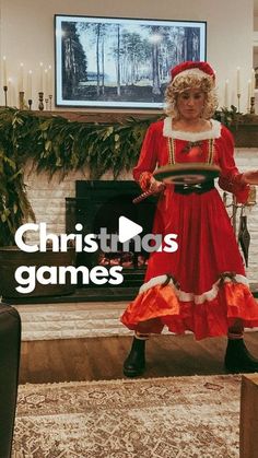 a woman in a red dress is standing near a fireplace and holding a video game controller