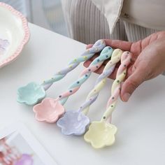 a person is holding five toothbrushes on a table next to a plate with flowers