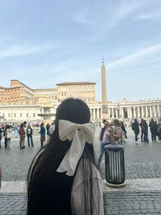 a woman with a bow on her head standing in front of an obelisk