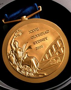 a gold medal with a blue ribbon around it's neck on a black plate