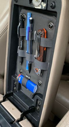 the inside of a car with tools and other items in it's holder,