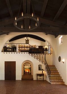 the inside of a house with stairs and lights in it's center area, next to a fire place