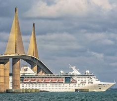 a cruise ship passing under a bridge in the ocean