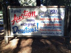 a sign that has been placed in the dirt near some trees and grass with words written on it