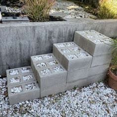 four cinder blocks are stacked on top of each other in front of some plants and gravel