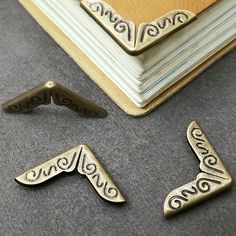 three antique style book ends sitting on the floor next to an open book and a pair of scissors