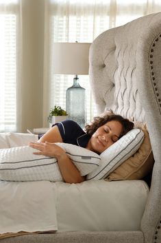 a woman is laying in bed with pillows