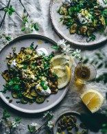 three plates filled with food sitting on top of a white table covered in green leaves