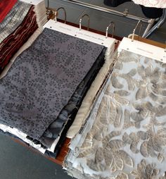 there are many different fabric samples on the table and one is being folded up to dry