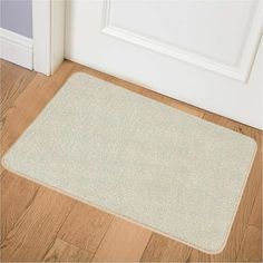 a white door mat sitting on top of a wooden floor next to an open door